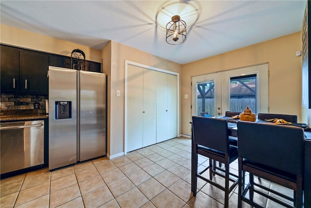 5213 Inverness Dr, Corpus Christi, TX 78413 - kitchen with appliances with stainless steel finishes, french doors, light tile patterned flooring, dark cabinets, and backsplash
