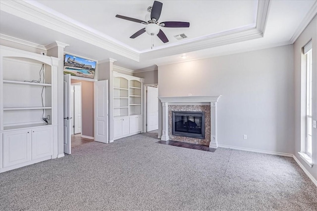 unfurnished living room featuring a raised ceiling, ceiling fan, and a healthy amount of sunlight