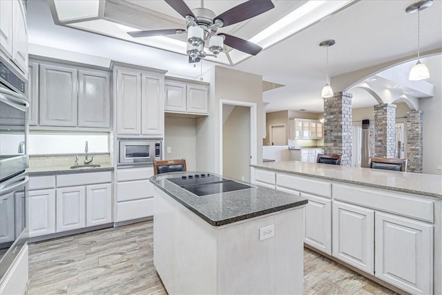 kitchen with decorative columns, white cabinets, a kitchen island, and decorative light fixtures