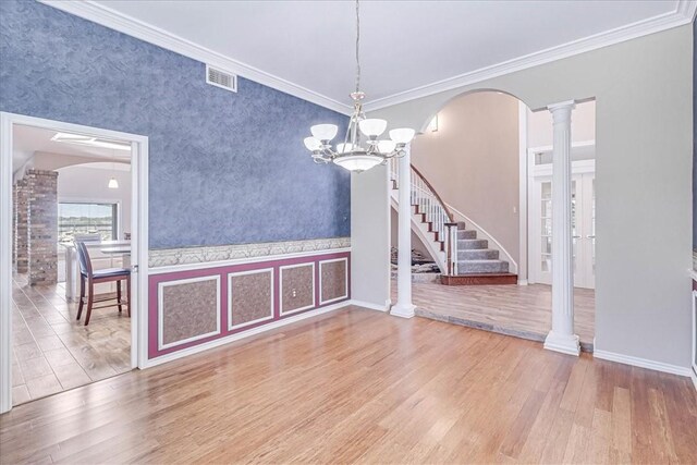 unfurnished dining area with wood-type flooring, decorative columns, crown molding, and an inviting chandelier