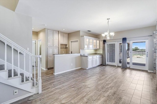 kitchen with hardwood / wood-style floors, decorative light fixtures, white cabinetry, and a notable chandelier