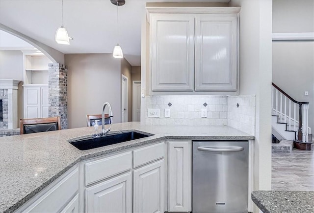 kitchen with a stone fireplace, sink, white cabinets, and pendant lighting