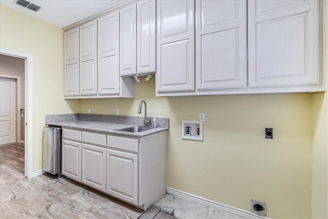 clothes washing area with sink, cabinets, washer hookup, hookup for an electric dryer, and light hardwood / wood-style floors