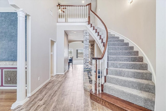 entryway featuring decorative columns, a towering ceiling, and wood-type flooring