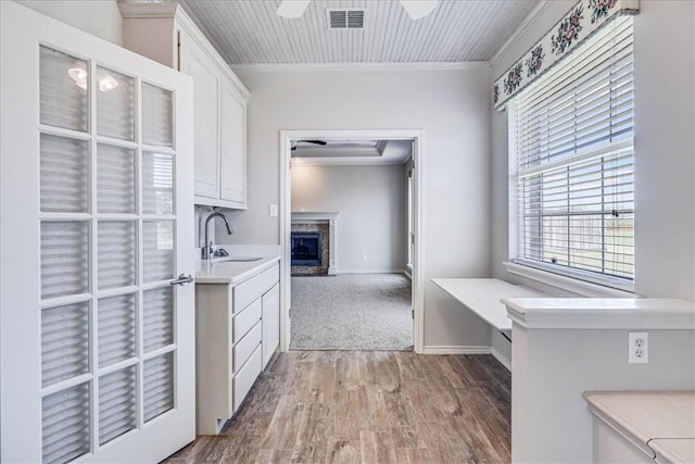 kitchen featuring white cabinetry, sink, a premium fireplace, and ornamental molding