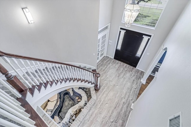 foyer featuring hardwood / wood-style flooring, a towering ceiling, and an inviting chandelier