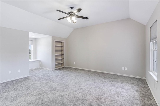 unfurnished bedroom featuring carpet flooring, ceiling fan, a spacious closet, and vaulted ceiling