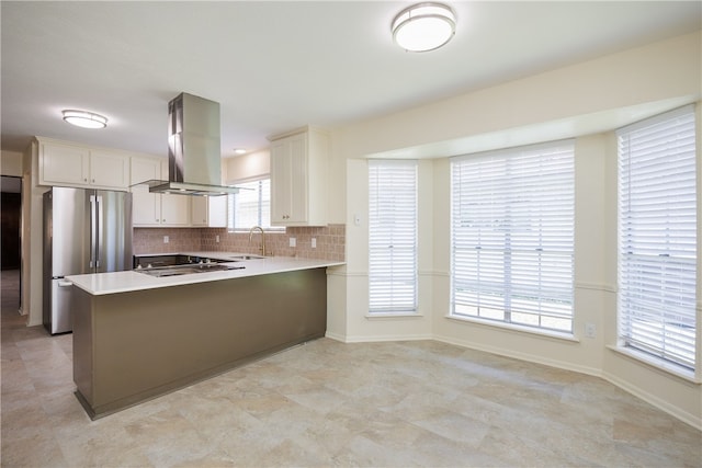 kitchen with white cabinetry, kitchen peninsula, island exhaust hood, and stainless steel fridge