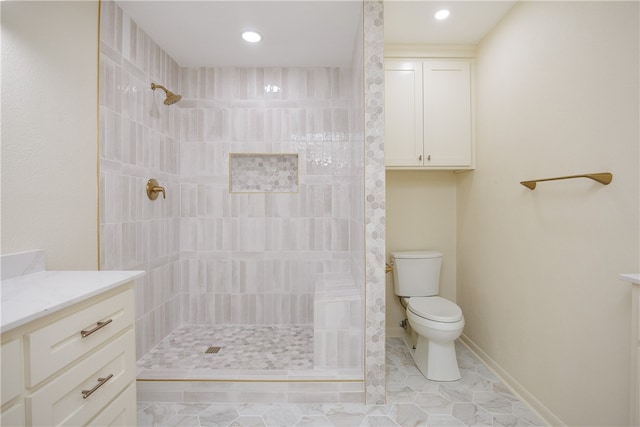 bathroom with toilet, vanity, and a tile shower