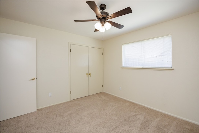 unfurnished bedroom featuring light colored carpet, ceiling fan, and a closet