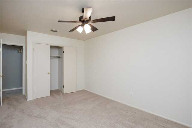 unfurnished bedroom with light colored carpet, ceiling fan, and a closet