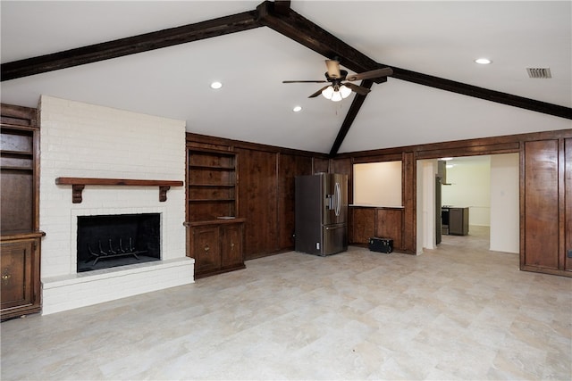 unfurnished living room with a brick fireplace, wood walls, vaulted ceiling with beams, and ceiling fan