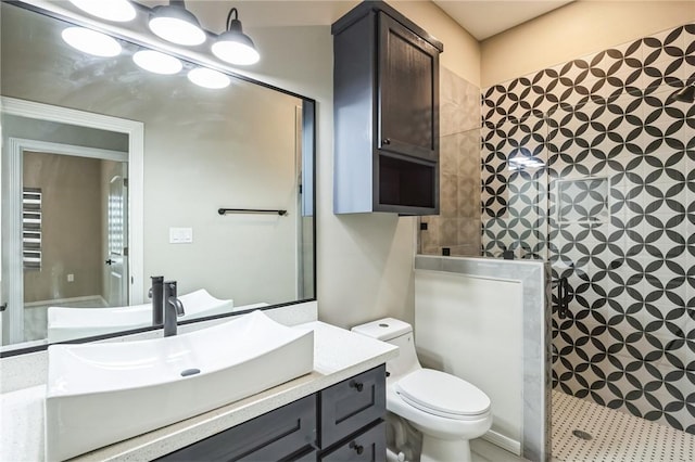 bathroom featuring a tile shower, vanity, and toilet