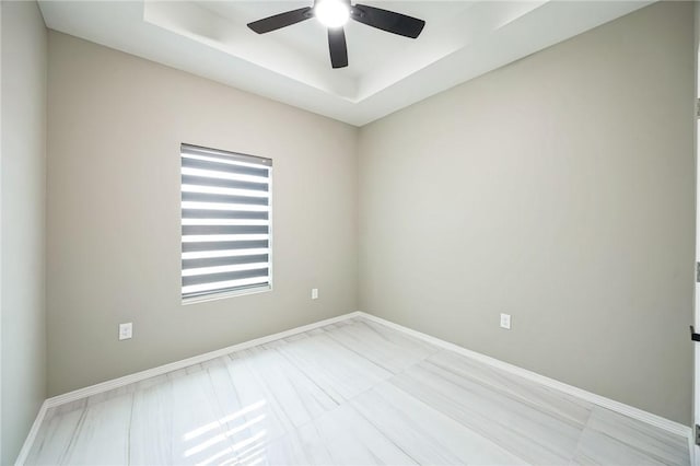 spare room with a raised ceiling and ceiling fan