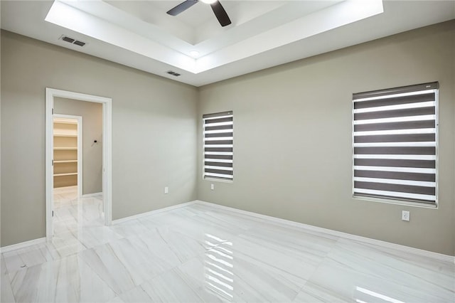 spare room featuring a raised ceiling and ceiling fan