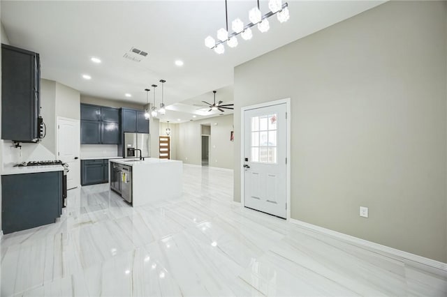 kitchen featuring sink, hanging light fixtures, appliances with stainless steel finishes, ceiling fan, and a kitchen island with sink