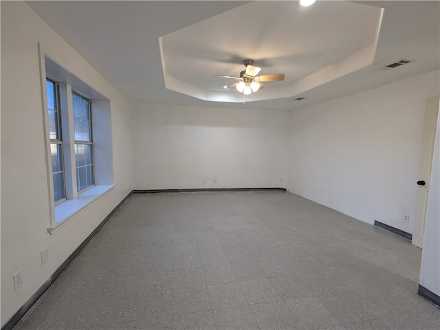 spare room with a tray ceiling and ceiling fan