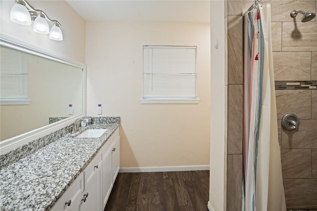 bathroom featuring baseboards, a tile shower, wood finished floors, and vanity