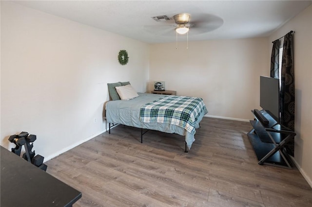 bedroom featuring ceiling fan, wood finished floors, visible vents, and baseboards