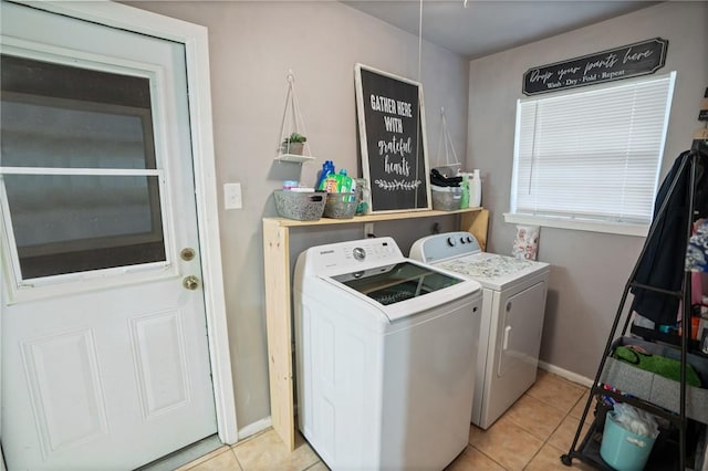 washroom with laundry area, baseboards, washing machine and clothes dryer, and light tile patterned floors