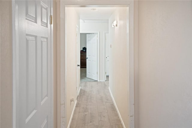 hall featuring light wood-style flooring and baseboards