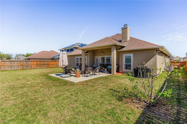 rear view of house featuring a lawn, a patio, a fenced backyard, ceiling fan, and stucco siding