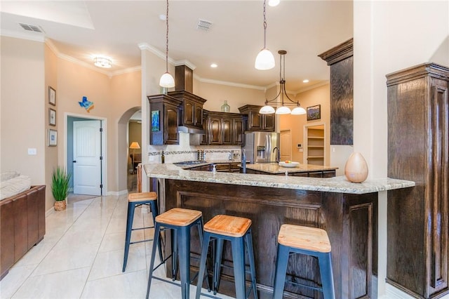 kitchen with arched walkways, visible vents, stainless steel refrigerator with ice dispenser, and dark brown cabinets