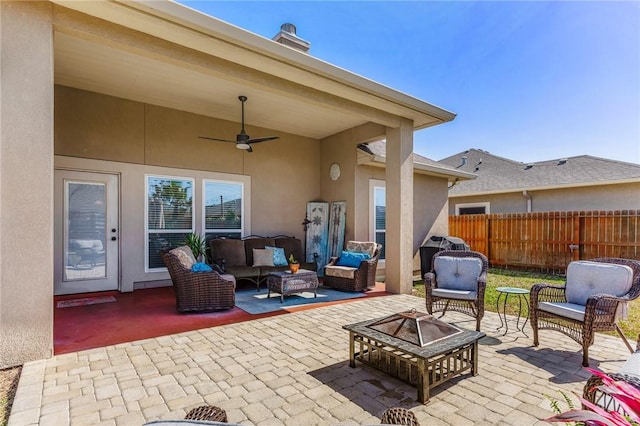 view of patio with ceiling fan, an outdoor living space with a fire pit, and fence