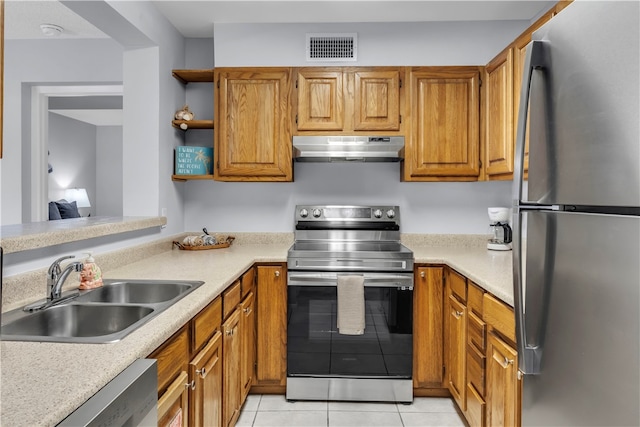 kitchen with appliances with stainless steel finishes, sink, and light tile patterned flooring