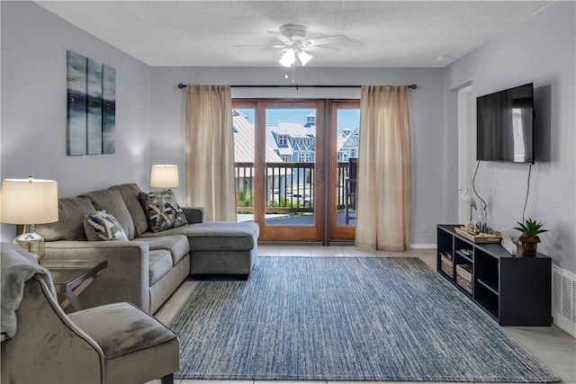 living room with light tile patterned flooring, ceiling fan, and a textured ceiling