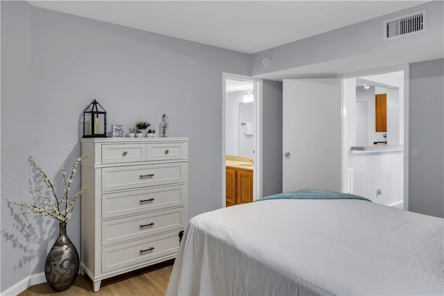 bedroom featuring ensuite bath and light hardwood / wood-style floors