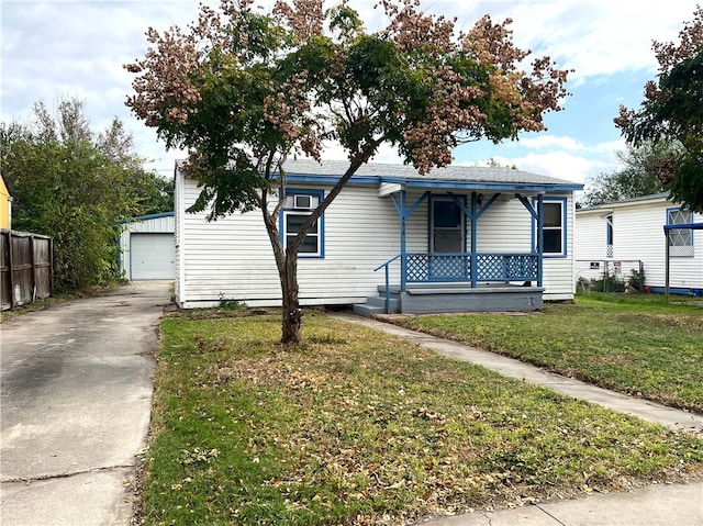 view of front of home with an outbuilding, covered porch, a front yard, and a garage