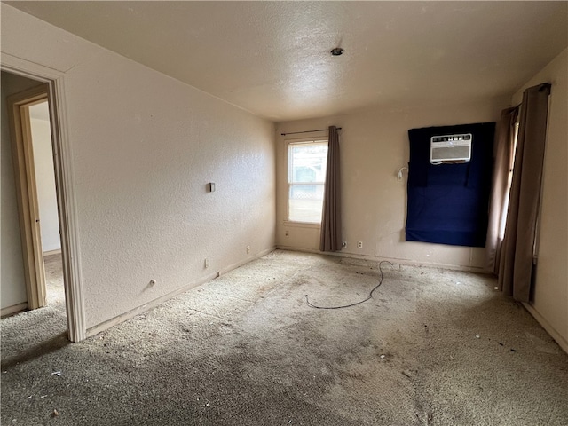 carpeted empty room featuring a wall mounted air conditioner and a textured ceiling