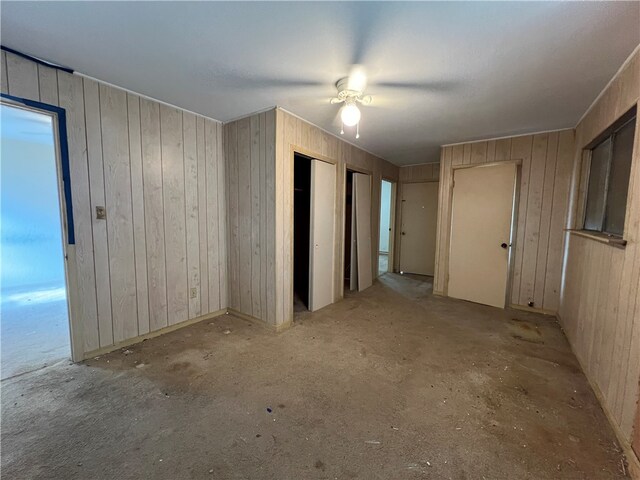 empty room with ceiling fan and wood walls