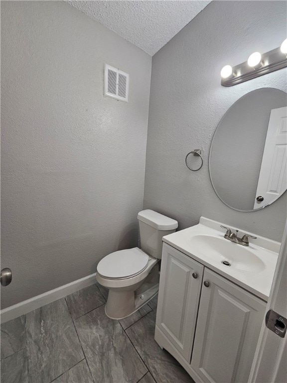 bathroom with vanity, toilet, and a textured ceiling