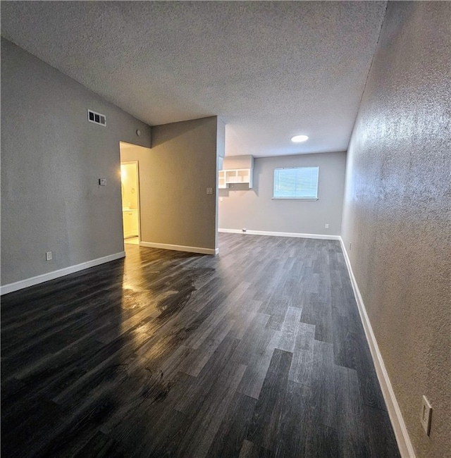 unfurnished room with dark wood-type flooring and a textured ceiling