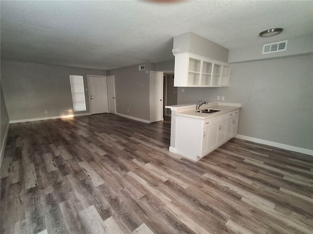 kitchen featuring sink, kitchen peninsula, dark hardwood / wood-style floors, a textured ceiling, and white cabinets