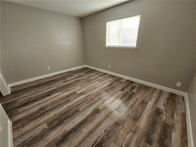 spare room featuring a textured ceiling and dark hardwood / wood-style flooring