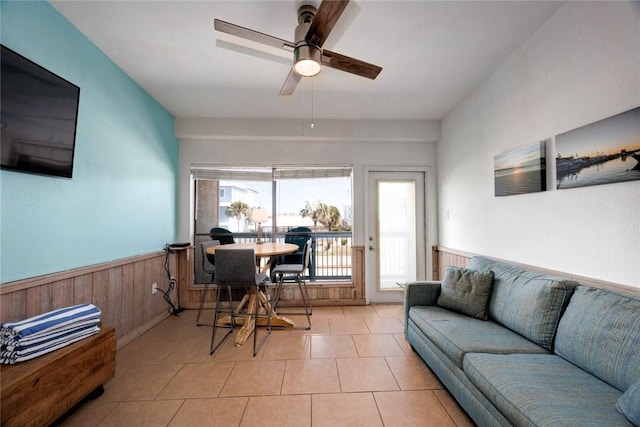 office with a ceiling fan, a wainscoted wall, wood walls, and light tile patterned floors