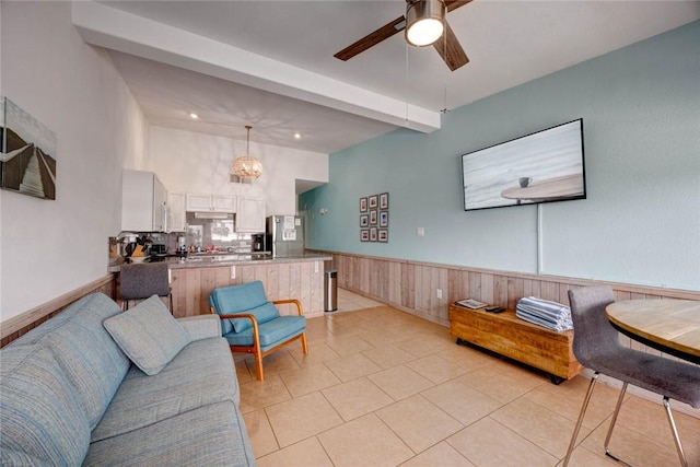 living room with a wainscoted wall, a ceiling fan, and light tile patterned flooring