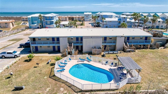 pool featuring a residential view, a water view, fence, and a patio