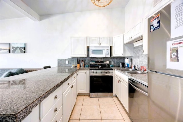 kitchen featuring stainless steel appliances, a sink, white cabinetry, and decorative backsplash