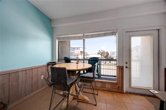 dining area featuring wood walls, wainscoting, and tile patterned floors