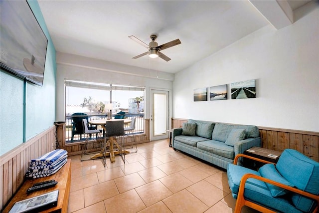 tiled living area with a wainscoted wall, wooden walls, and a ceiling fan