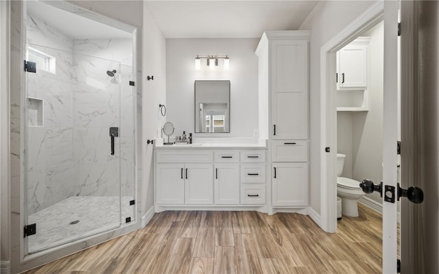 bathroom featuring walk in shower, hardwood / wood-style floors, vanity, and toilet