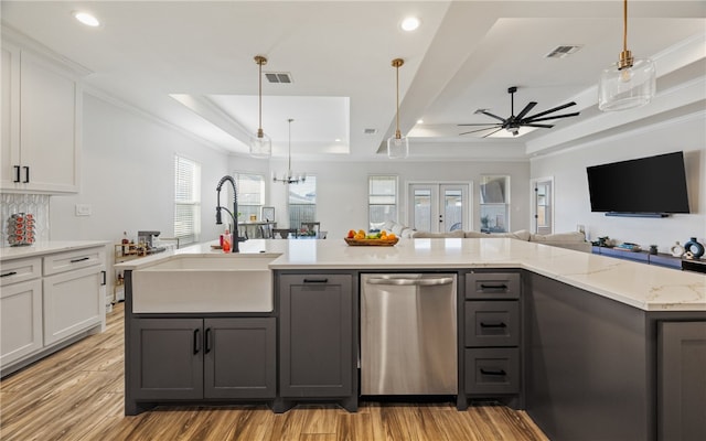 kitchen with sink, dishwasher, a tray ceiling, an island with sink, and white cabinets