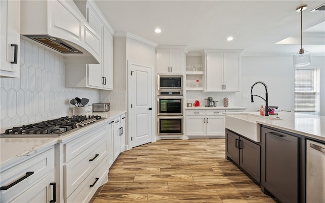 kitchen featuring premium range hood, sink, decorative light fixtures, stainless steel appliances, and white cabinets