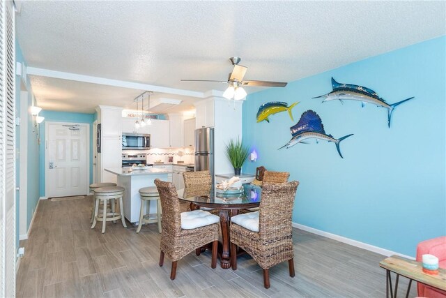 14810 Windward Dr Unit 203, Corpus Christi, TX 78418 - dining room featuring light wood-type flooring, a textured ceiling, and ceiling fan