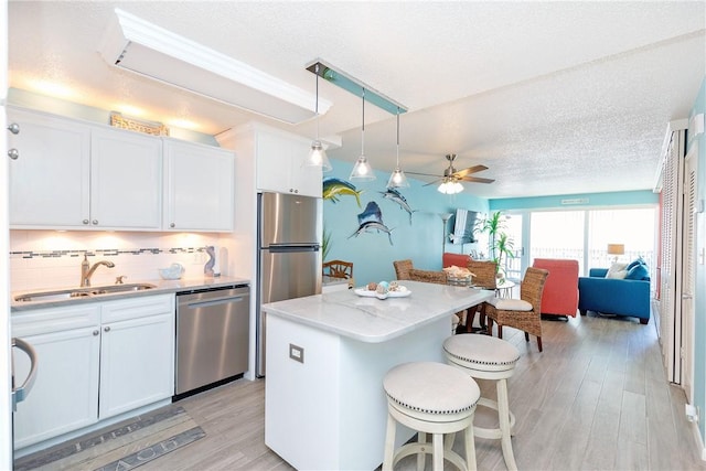 14810 Windward Dr Unit 203, Corpus Christi, TX 78418 - kitchen featuring stainless steel appliances, a kitchen breakfast bar, ceiling fan, light wood-type flooring, and white cabinets