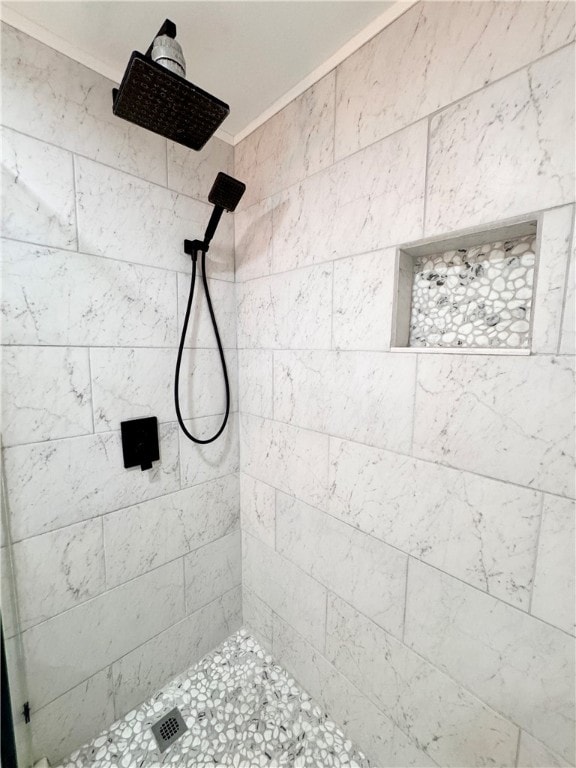 bathroom featuring ornamental molding and tiled shower